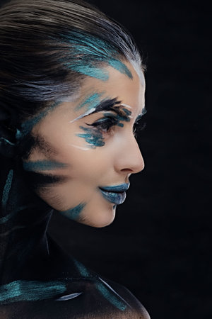 Side view close up portrait of a woman with artistic make up on dark background.