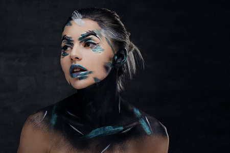 Portrait of a woman with artistic make up on a face and neck isolated on dark grey background.の写真素材