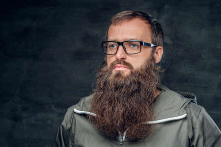 Brutal bearded hipster male in a hood on grey background.の写真素材