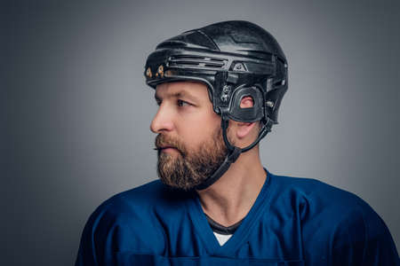 Close up portrait of ice-hockey player in safety helmet on grey vignette background.の写真素材