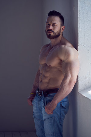 Portrait of shirtless  bodybuilder male model in a jeans near window.の写真素材