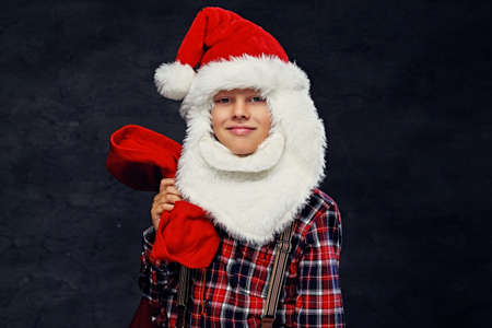 Portrait of teenage boy dressed in Santa's holiday costume and a plaid shirt.の写真素材