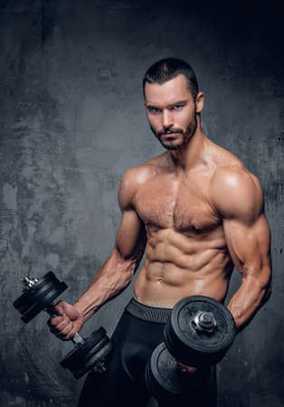 Portrait of muscular shirtless bearded male holds dumbbells.の写真素材