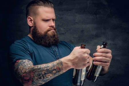 Alcohol addiction. Bearded male looking at two empty beer bottles.の写真素材