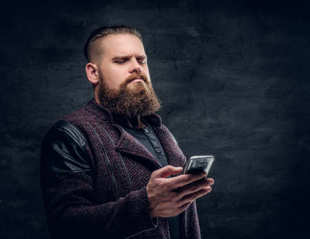 Brutal bearded hipster male texting an SMS on a smartphone.の写真素材