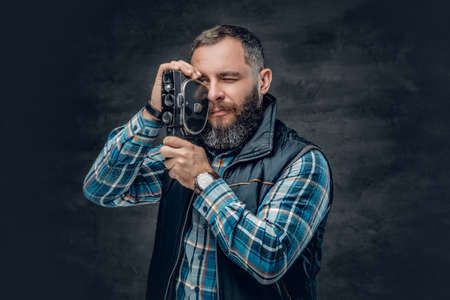Portrait of bearded middle age male holds vintage 8 mm video camera over grey background.の写真素材