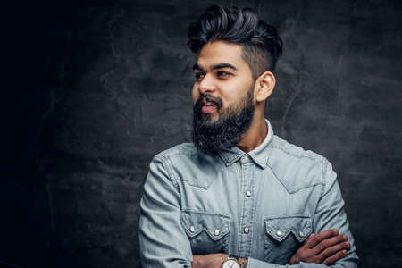 Studio portrait of stylish bearded Indian man in a blue shirt over grey background.の写真素材