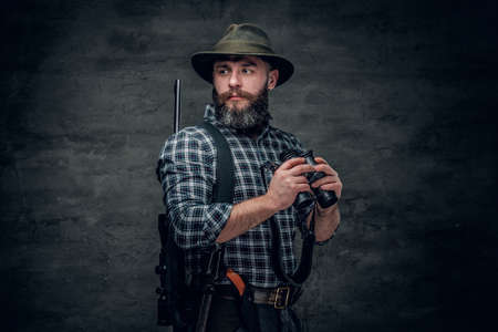 Studio portrait of bearded hunter male wearing a plaid fleece shirt holds a rifle.の写真素材