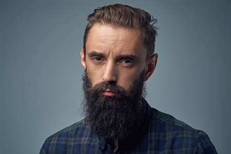 Close up portrait of bearded male over grey background.