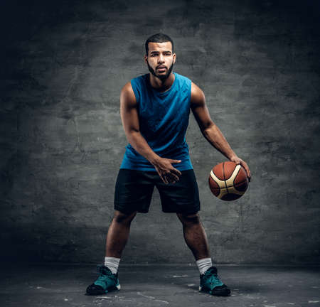 Full body studio portrait of a black basketball player playing with a ball.の写真素材