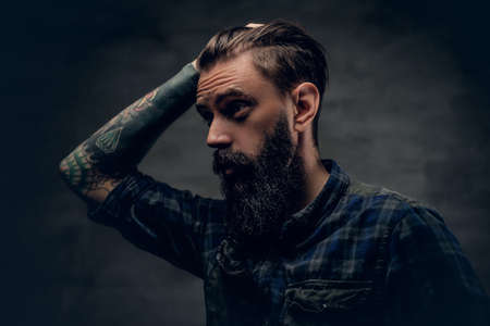 Bearded male with tattoo on arm touches his head.の写真素材