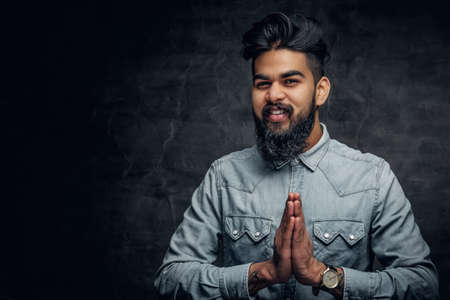 Studio portrait of stylish bearded Indian man in a blue shirt over grey background.の写真素材