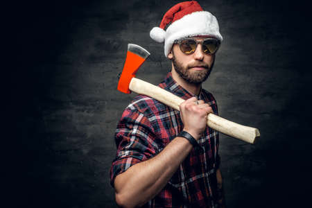 Portrait of a bearded man wearing Santa's hat and holds axe.の写真素材