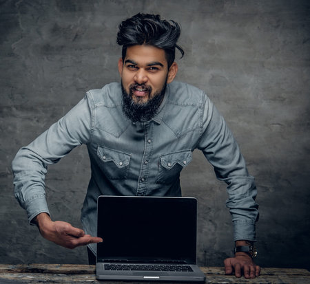 A handsome Indian man presenting a laptop.