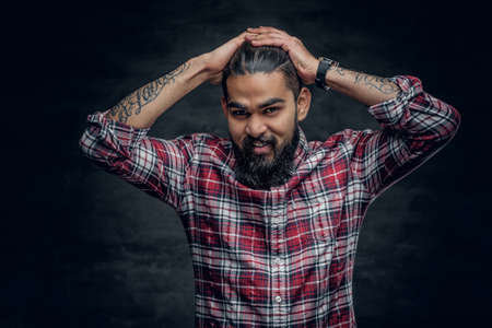 Attractive bearded Indian man in plaid fleece shirt over grey background.の写真素材