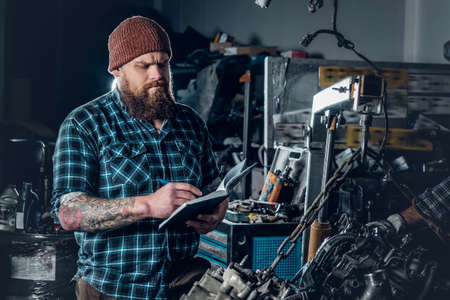 Bearded mechanics male inspecting car's engine in a garage.の写真素材
