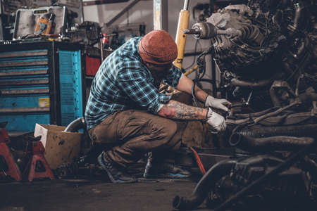 Bearded male repairing car's engine in a garage.の写真素材
