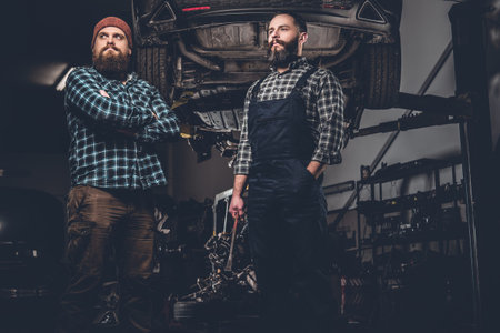 Portrait of two bearded mechanics in a garage.