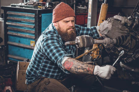 Bearded male repairing car's engine in a garage.の写真素材