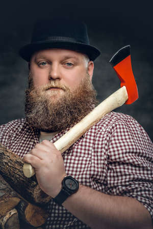 Fat bald, bearded man holds an axe and fire woods.の写真素材