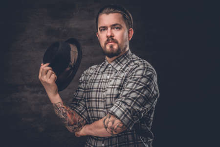 Bearded man with tattooed arms wearing a plaid fleece shirt and a wool vintage hat.の写真素材