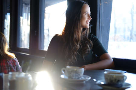 Portrait of smiling brunette woman drinks morning coffee in a cafe.の写真素材