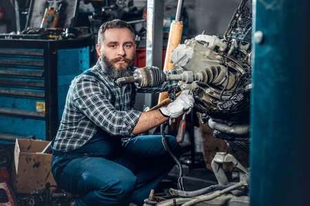 Bearded mechanic man repairing the car's engine in a garage.の写真素材