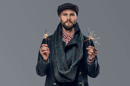 Casual bearded male in a grey jacket and a wool cap isolated on grey background.の写真素材