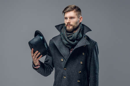 Portrait of a bearded man dressed in a grey jacket holds a cylinder hat.の写真素材