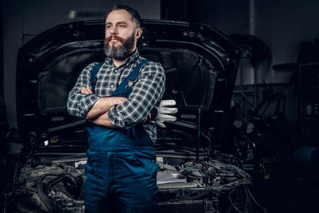Portrait of bearded mechanic man near the car in a garage.の写真素材