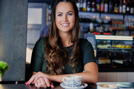Portrait of smiling brunette woman drinks morning coffee in a cafe.の写真素材