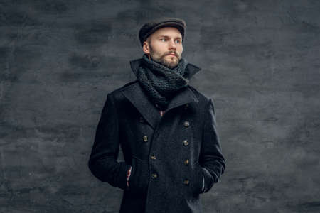 Portrait of a bearded hipster man dressed in a gray jacket and a wool cap isolated on grey background.の写真素材