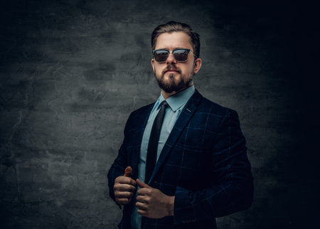 Portrait of stylish bearded hipster male dressed in a jacket, bow tie and sunglasses.の写真素材
