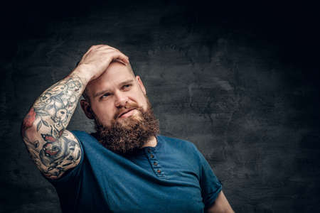 Bearded fat male with tattoo on arms posing over grey background.の写真素材