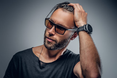 Portrait of handsome macho male dressed in a grey t shirt and sunglasses isolated on grey background.の写真素材