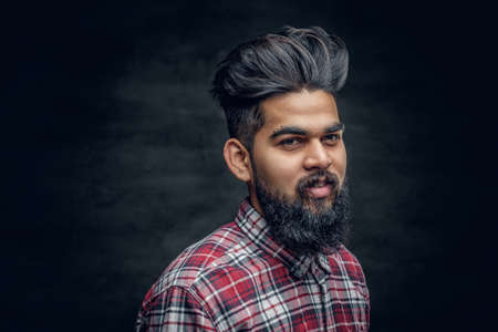 A handsome bearded Indian male dressed in a fleece shirt over grey vignette background.の写真素材