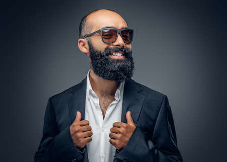 Portrait of bearded businessman dressed in a suit isolated on grey background.の写真素材