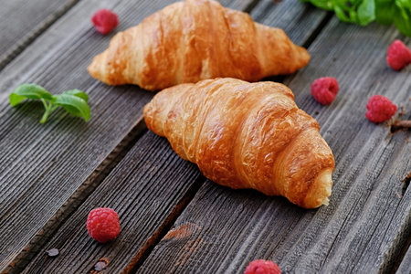 Two fresh croissants on a wooden table.の写真素材