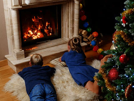 Kids lying on warm blanket and looking in to the fireplace. Christmas time.の写真素材