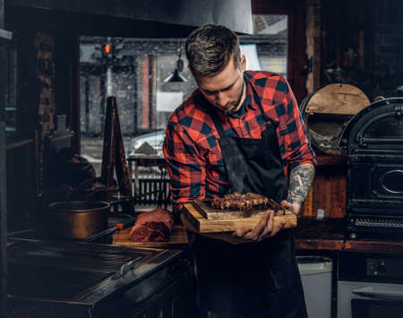 Handsome bearded cheef cook prepairing a meat on a kitchen.の写真素材