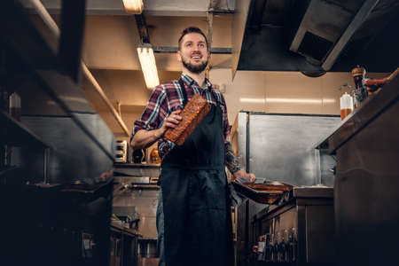 Handsome bearded cook holds bread on a kitchen.の写真素材