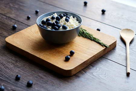 Curb with blueberry and herbs in a cup on a wooden desk.