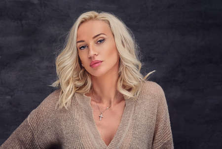 Portrait of sexual blond female with curly hair over grey background.