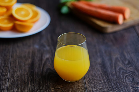 Orange juice in a glass and delicious carrot on a table.
