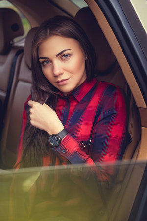 Brunette female in a red fleece shirt sits in a car.
