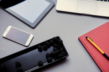 Berries in a workspace near a laptop and other electronic gadgets.