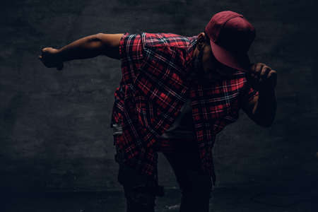 A man dressed in a red fleece shirt and a cap over posing in a shadow.の写真素材