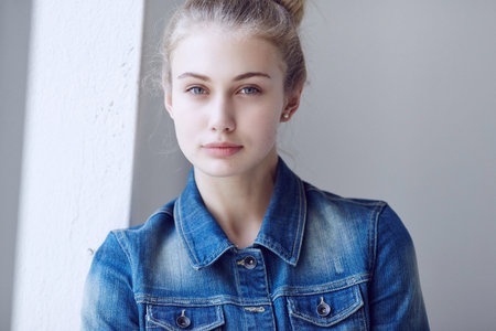 Portrait of a blue eyed blond female dressed in a denim jacket.の写真素材