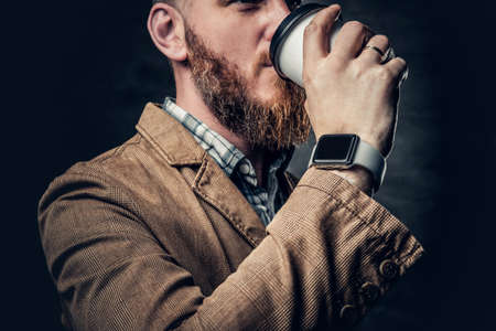 Stylish redhead bearded hipster male drinks coffee.の写真素材