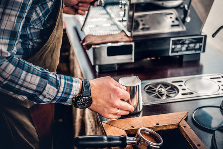 Close up image of a man preparing cappuccino in a coffee machine.
